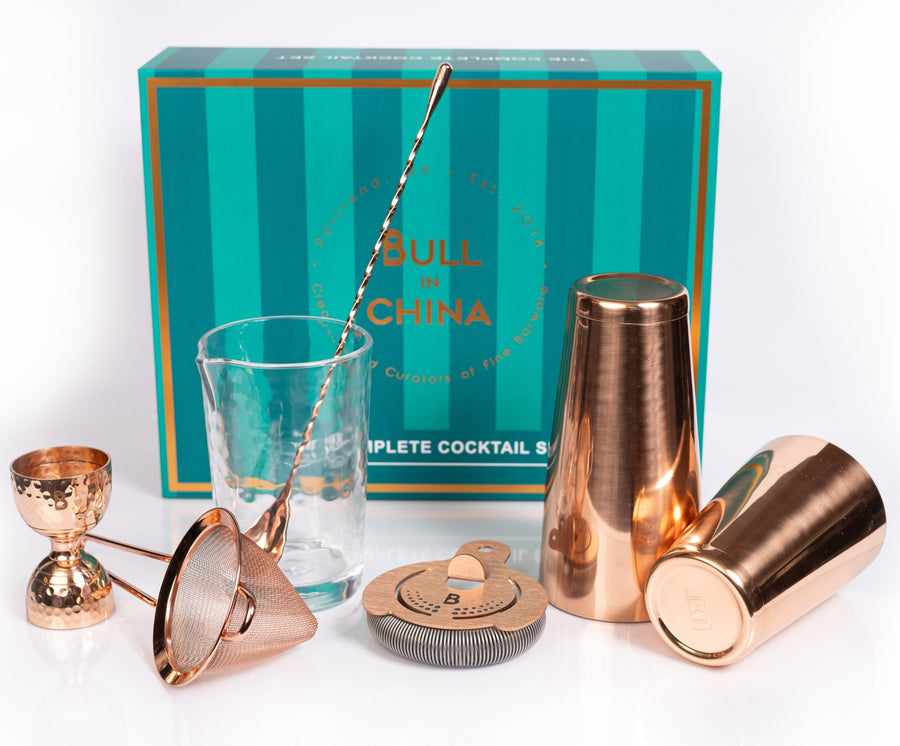 The Complete Cocktail Set with bartending tools, including a shaker, jigger, strainer, and glass, perfect for home bars.